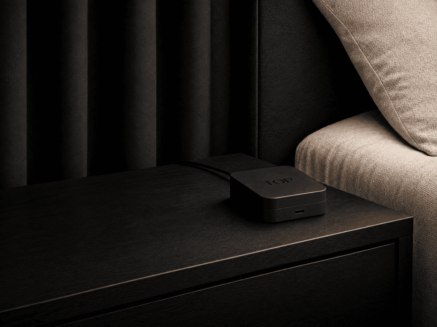 A TOP device on the nightstand of a dark hotel room