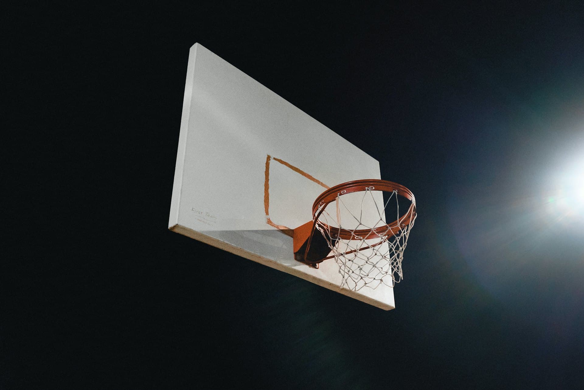 A basketball dropping through the hoop under arena lights
